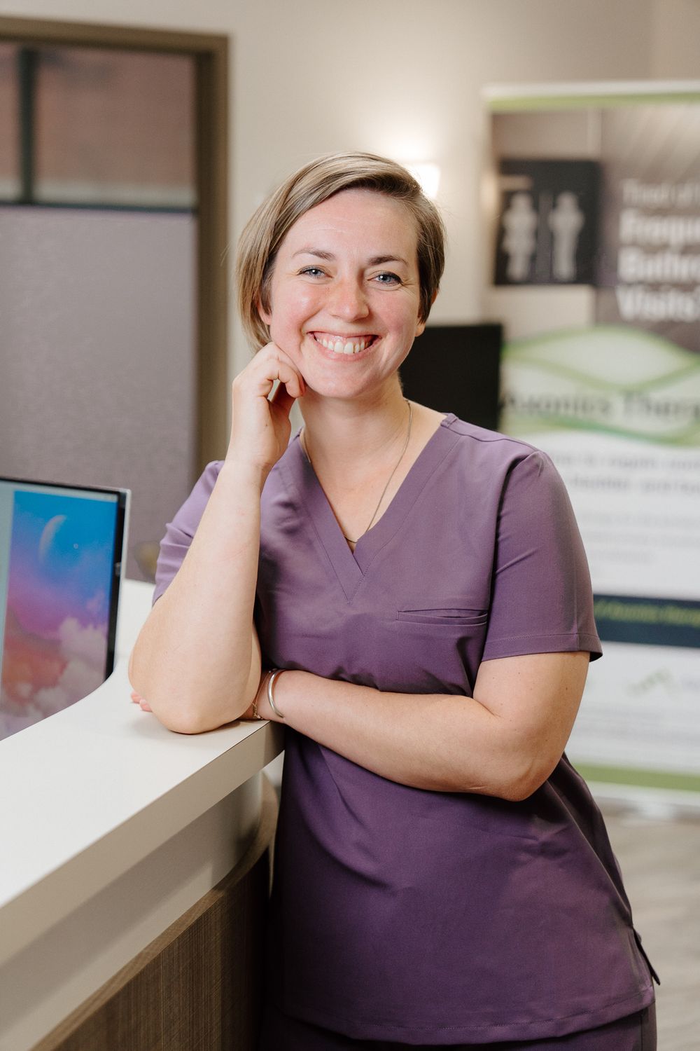 Smiling healthcare professional in purple scrubs.